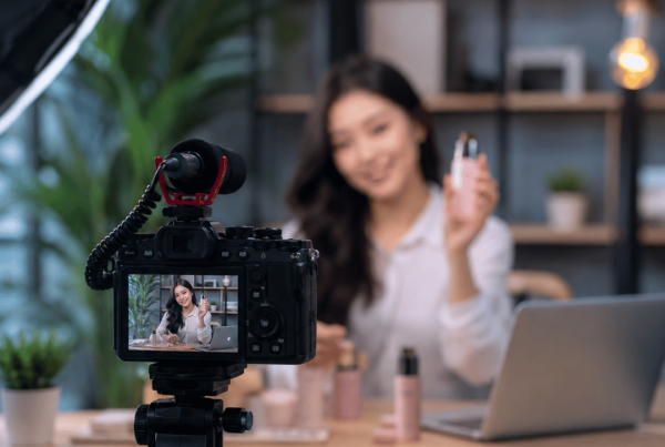 Realistic advertisement video production setup showing a content creator presenting a product in front of a professional camera in a modern studio.