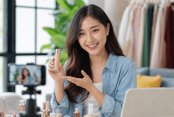 Young influencer creating beauty content for a brand using a smartphone camera in a home studio