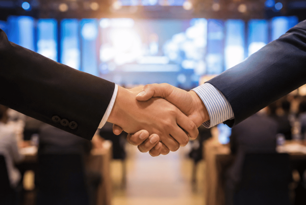Realistic business sponsorship handshake at a corporate event, representing brand partnerships, credibility and customer trust.