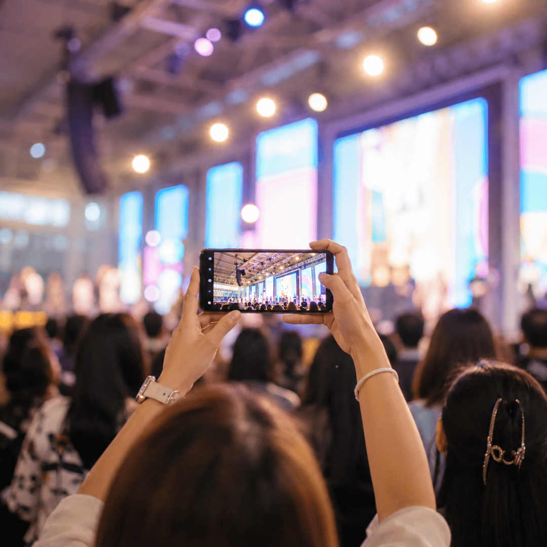 Person recording a live event with a smartphone for event video marketing content